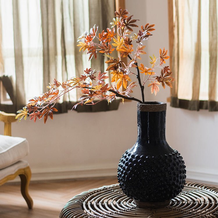Large navy blue coarse pottery vase with bubbled texture on a wicker table with branches on Tampa Home & Garden Store