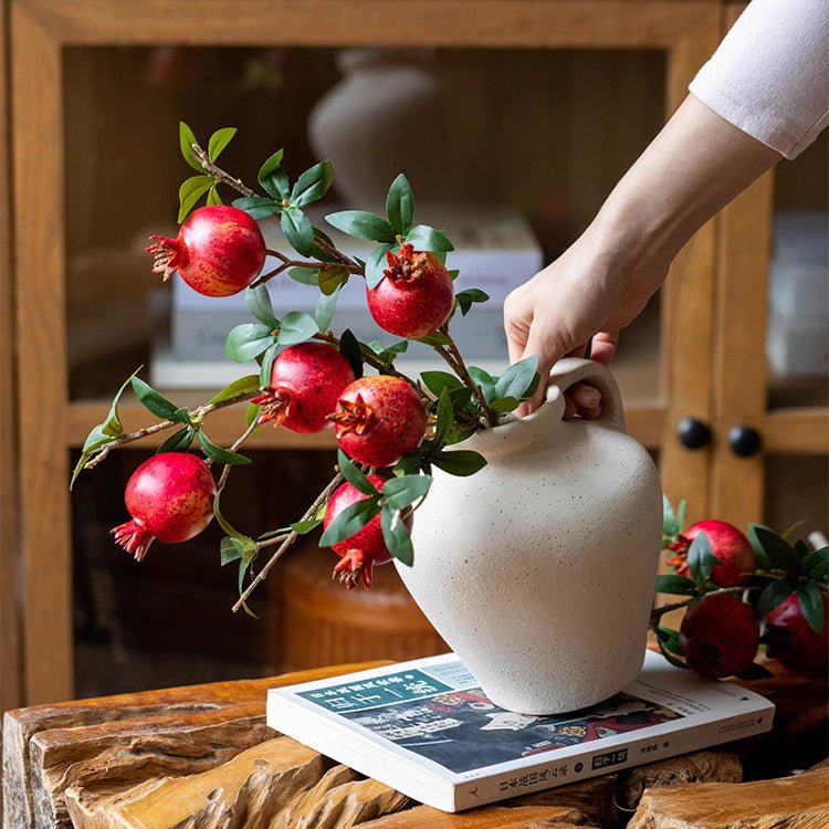 Faux Pomegranate Stem 15in tall with red fruit and green leaves in white ceramic vase on Tampa Home & Garden Store