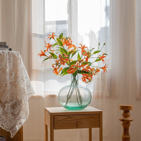 Faux Silk Flame Lily stem 29in tall, orange blooms in a glass vase on a wood side table on Tampa Home & Garden Store