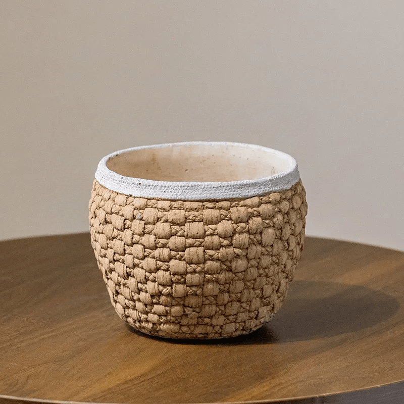 Woven rattan cement planter with white rim, round earthy pot on wooden table on Tampa Home & Garden Store