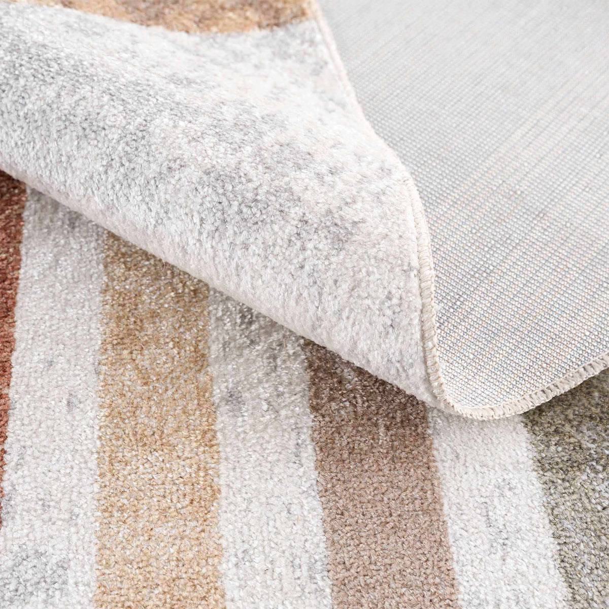 Giza washable area rug by Boutique Rugs; plush cream gray pile with beige accents, stacked rugs on display on Tampa Home & Garden Store