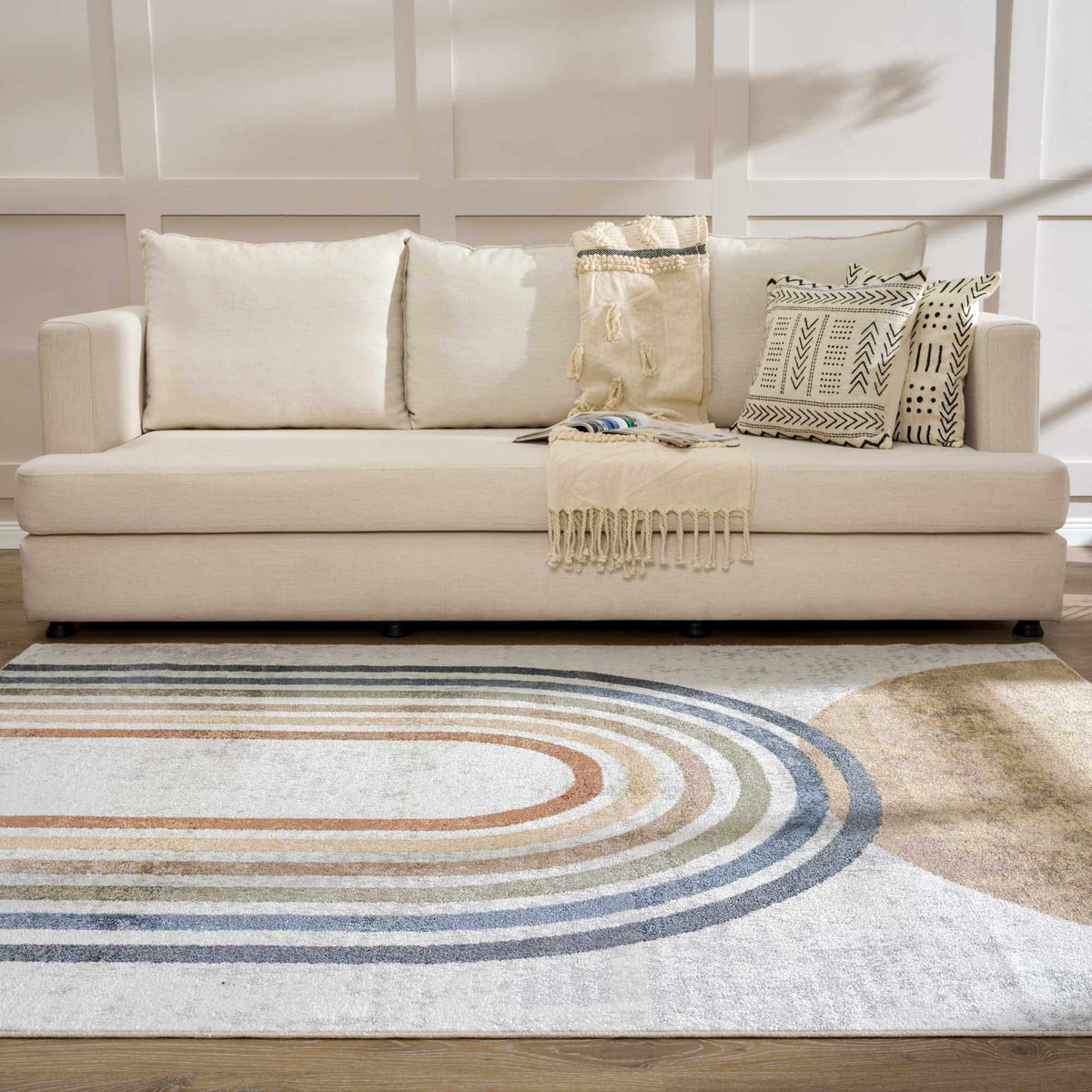 Giza Washable Area Rug with concentric circle pattern in blues and browns under a beige sofa on Tampa Home & Garden Store