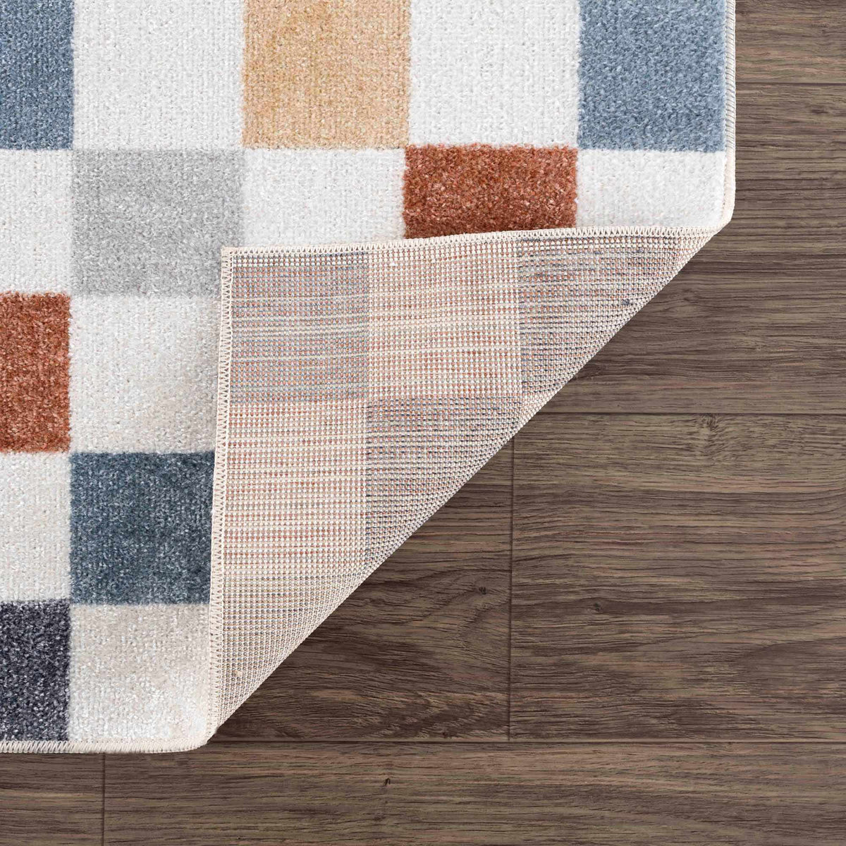 Alie Colorful Checkered Washable Rug with white, blue, peach and rust blocks on wood floor on Tampa Home & Garden Store