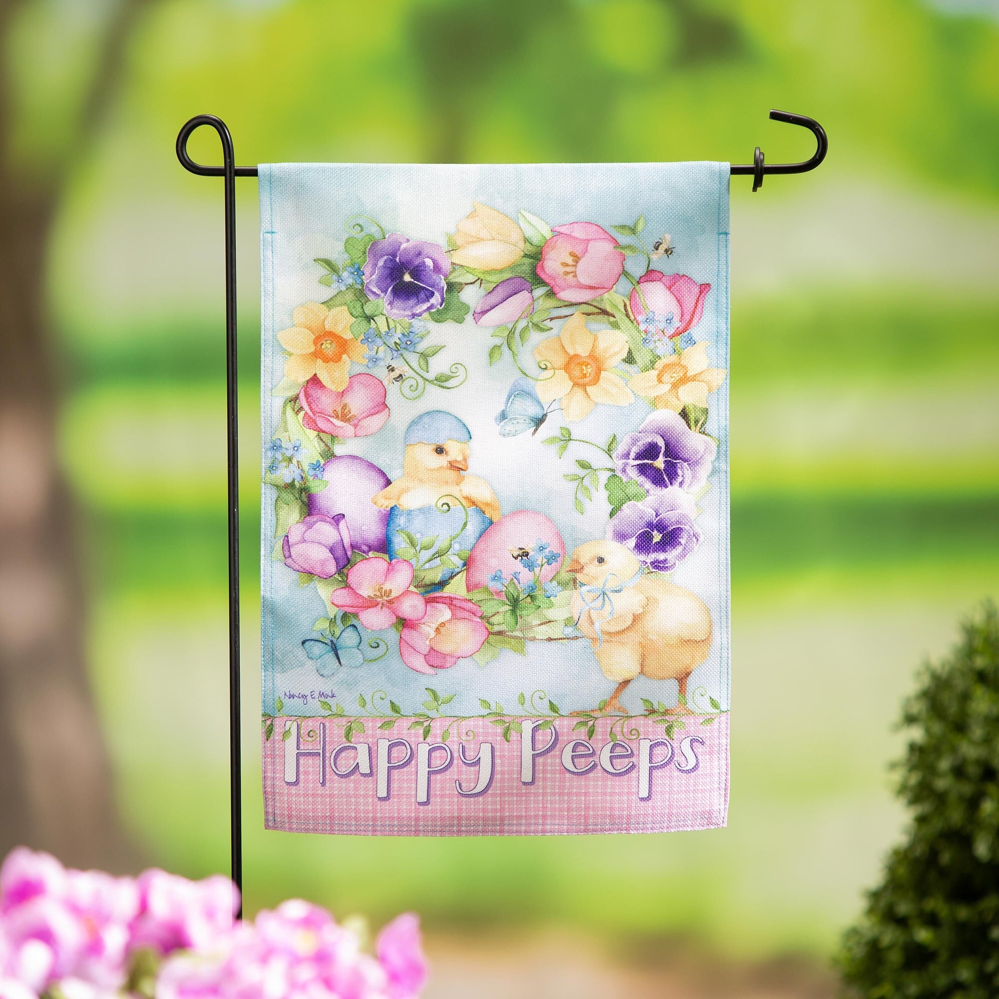 Spring Has Hatched Burlap Garden Flag with pastel flowers on a black metal stand on Tampa Home & Garden Store