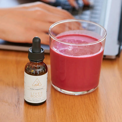 Liver Boost herbal supplement bottle by OWL Venice beside pink drink in a glass on a wood table on Tampa Home & Garden Store