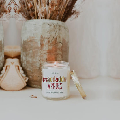 Mac Apple Candle by Gia Roma in a clear glass jar with a gold lid beside on white surface on Tampa Home & Garden Store