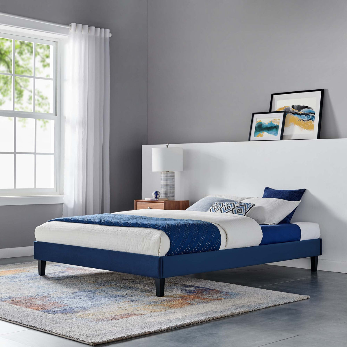 Blue velvet platform bed by Modway with white bedding and navy bed skirts in a modern bedroom on Tampa Home & Garden Store
