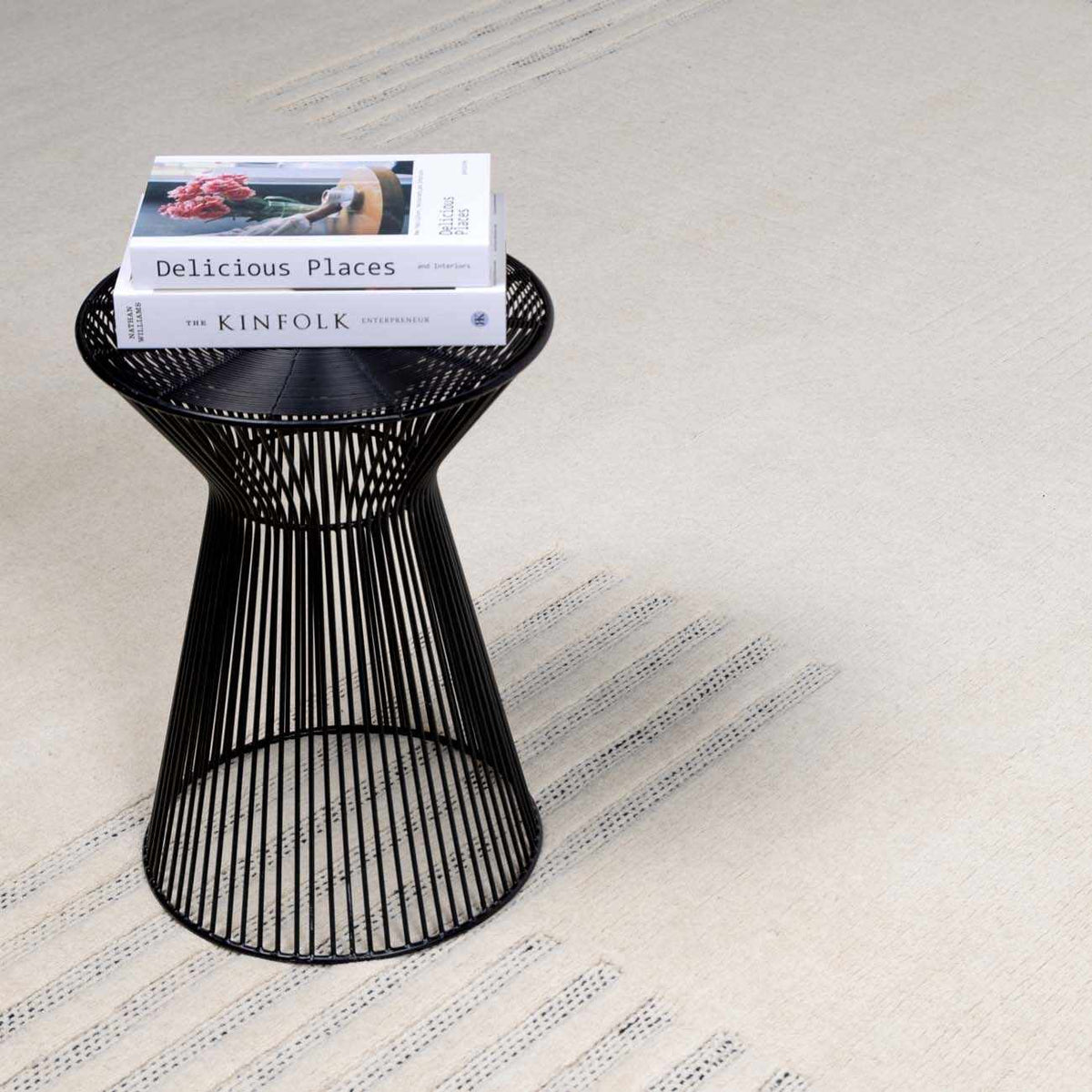Yulia Wool Area Rug on beige textured floor with a black wire pedestal table and magazines on Tampa Home & Garden Store