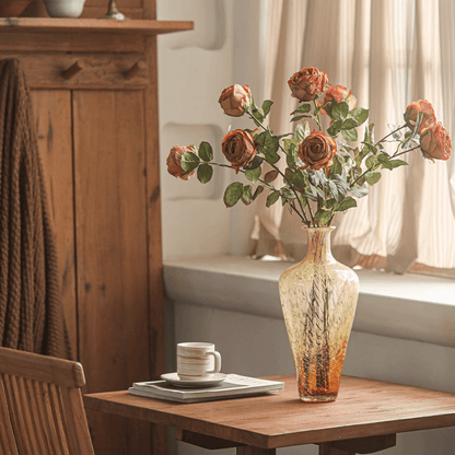 Artificial rose stem bouquet with multiple orange roses in an amber glass vase on a wooden table on Tampa Home & Garden Store