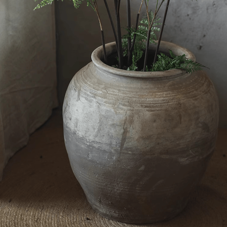 Round earthenware pot by RusticReach in gray glaze with earthy banding; plant stems visible on Tampa Home & Garden Store