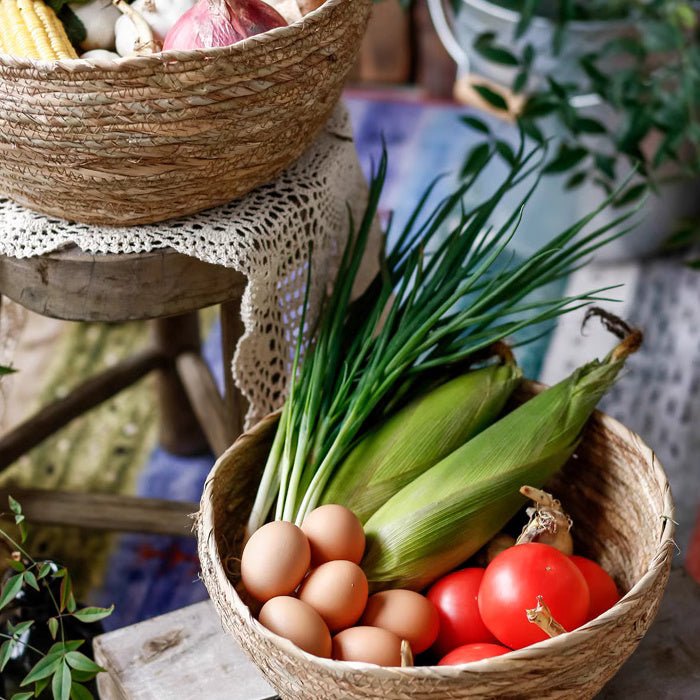 Two natural seagrass bowl baskets by RusticReach with eggs, corn, onions, and tomatoes on Tampa Home & Garden Store