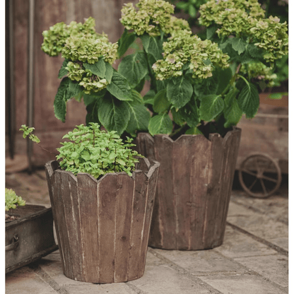 Two brown spliced solid wood round planters with plants on Tampa Home & Garden Store