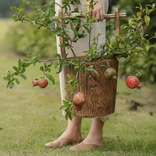 Old-fashioned wooden round bucket with greenery and hanging pomegranate fruit RusticReach on Tampa Home & Garden Store