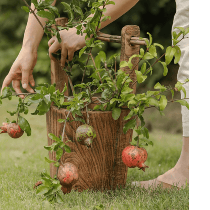 Old-fashioned round wooden bucket with rustic brown wood and three hanging pomegranates on Tampa Home & Garden Store