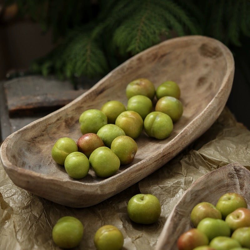 Retro wooden boat-shaped fruit platter in natural wood tone with a dozen green plums on Tampa Home & Garden Store