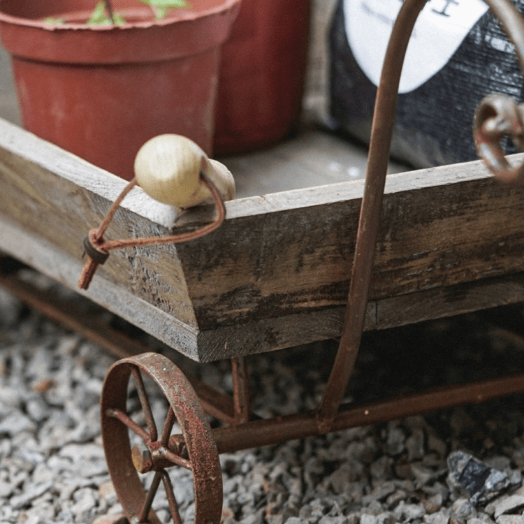 Small decorative wooden wagon flower cart with iron wheels and a plant pot on Tampa Home & Garden Store