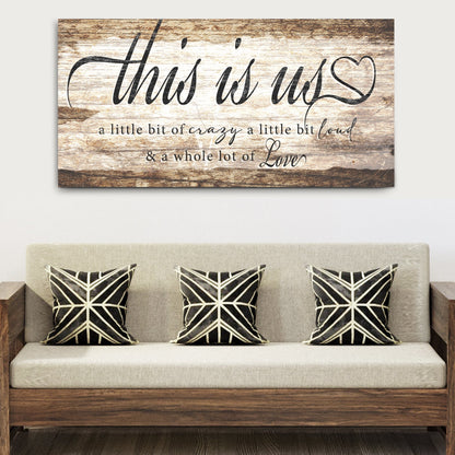 This Is Us Sign canvas with rustic wood backdrop, black cursive lettering and heart motif on Tampa Home & Garden Store