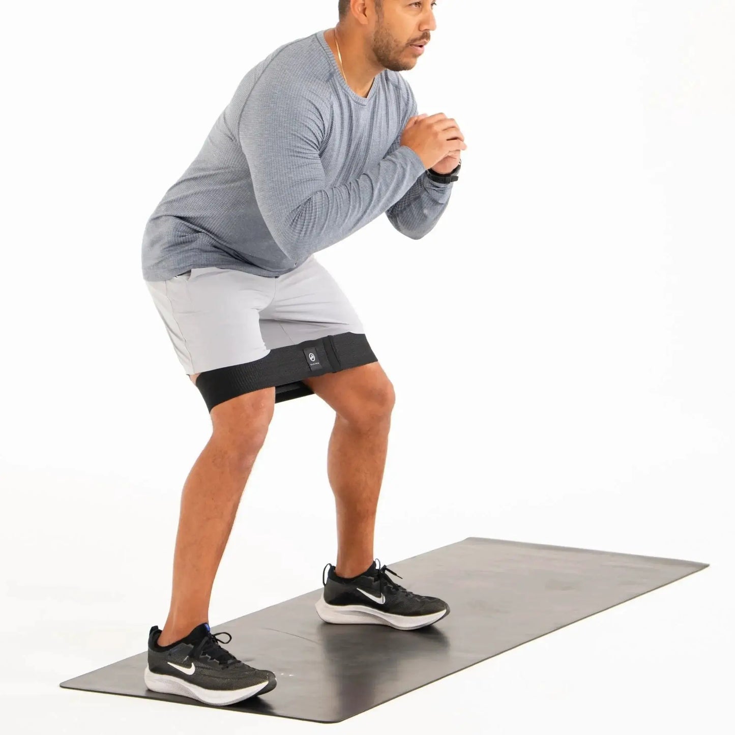 Full Body System muscle release tool worn as a black thigh strap during squat on mat on Tampa Home & Garden Store