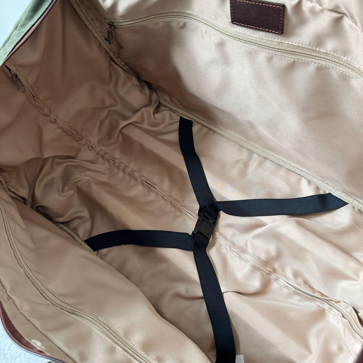 Maxwell waxed canvas rolling duffel bag interior with tan lining, zip pocket, and black straps on Tampa Home & Garden Store