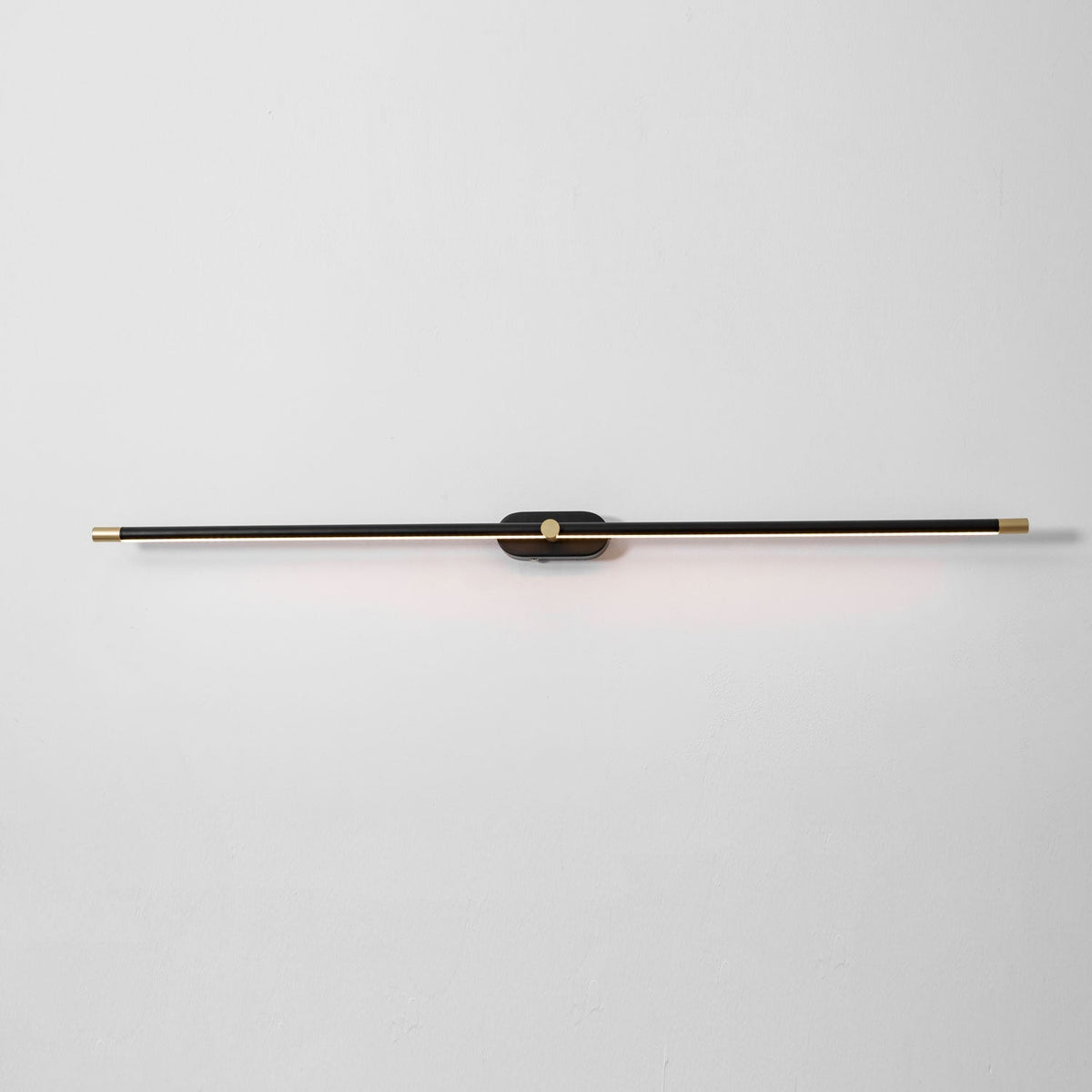 Rechargeable linear LED wall lamp Moktan Sabai in black with brass ends, wall-mounted on Tampa Home & Garden Store