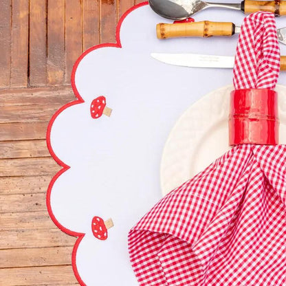 Mushroom placemat with red stitched scalloped border and mushroom motifs on a wooden table on Tampa Home & Garden Store