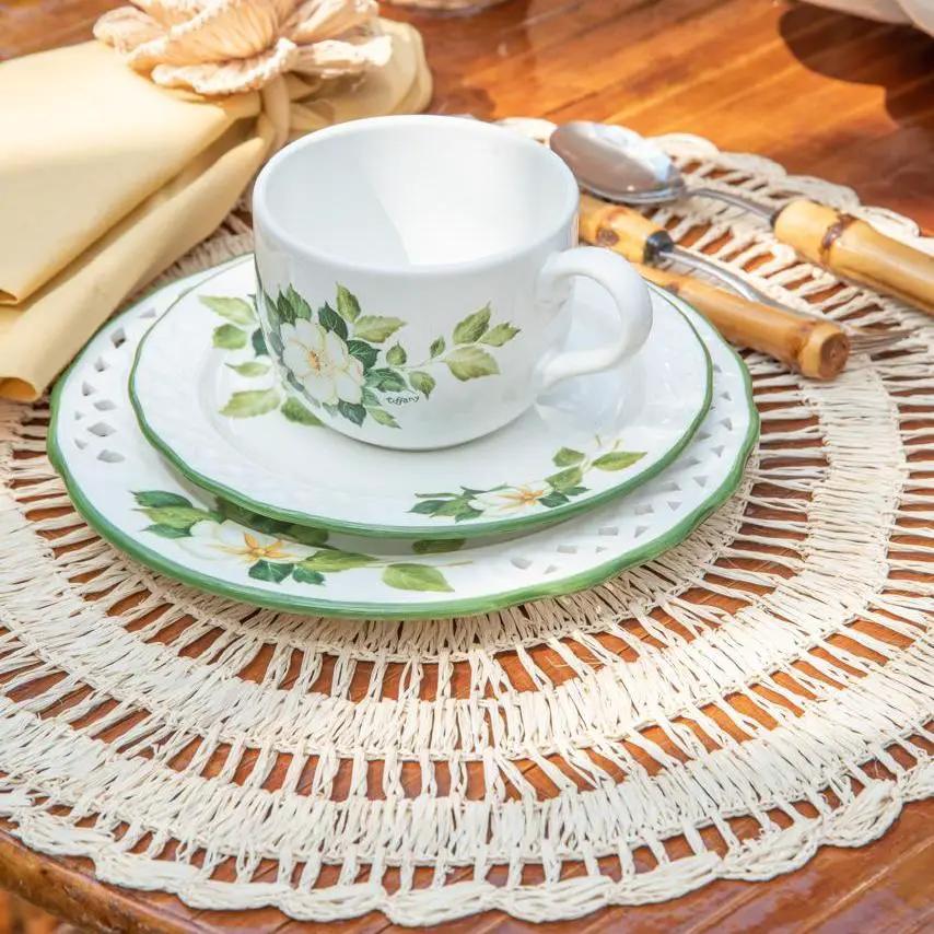 Buriti Straw Placemats with woven round mat, white floral dishware, and a Talah Home teacup on Tampa Home & Garden Store