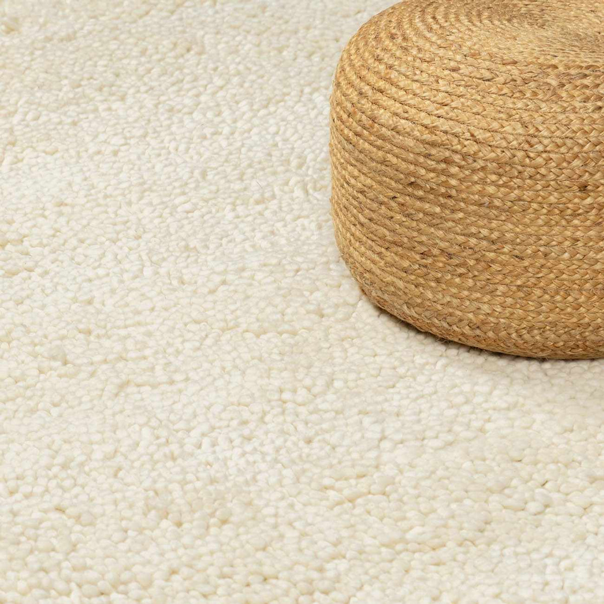 Oakridge Area Rug cream shag texture with round natural braided jute pouf on beige floor on Tampa Home & Garden Store