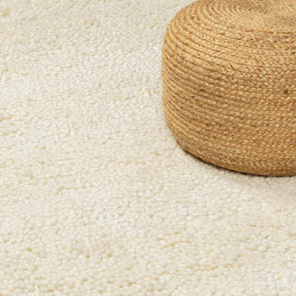 Oakridge Area Rug cream shag texture with round natural braided jute pouf on beige floor on Tampa Home & Garden Store