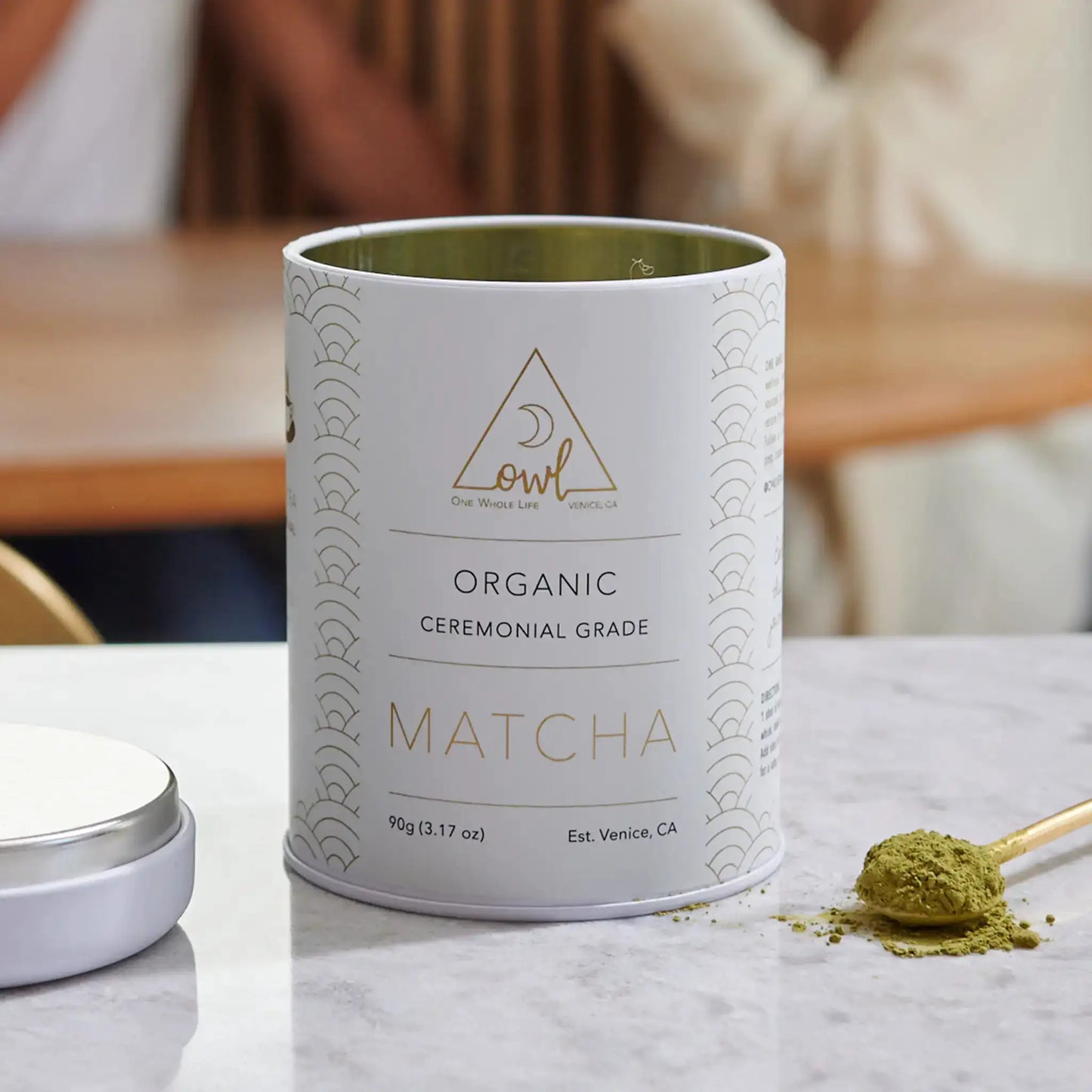 Organic matcha powder tin by OWL Venice, can with gold logo and matcha on marble surface on Tampa Home & Garden Store