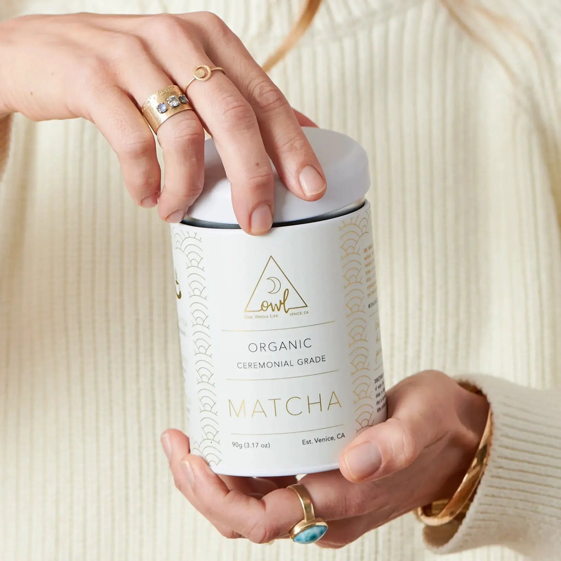 Matcha tin opening by hands with gold rings OWL Venice label visible on white container on Tampa Home & Garden Store