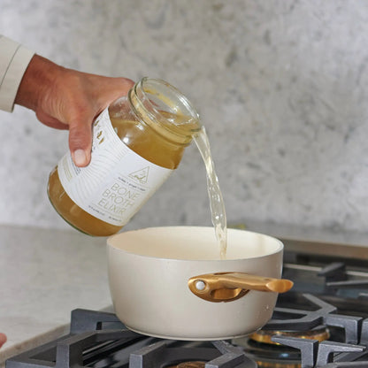 Bone broth bottle by OWL Venice being poured into a pot; organic broth on Tampa Home & Garden Store