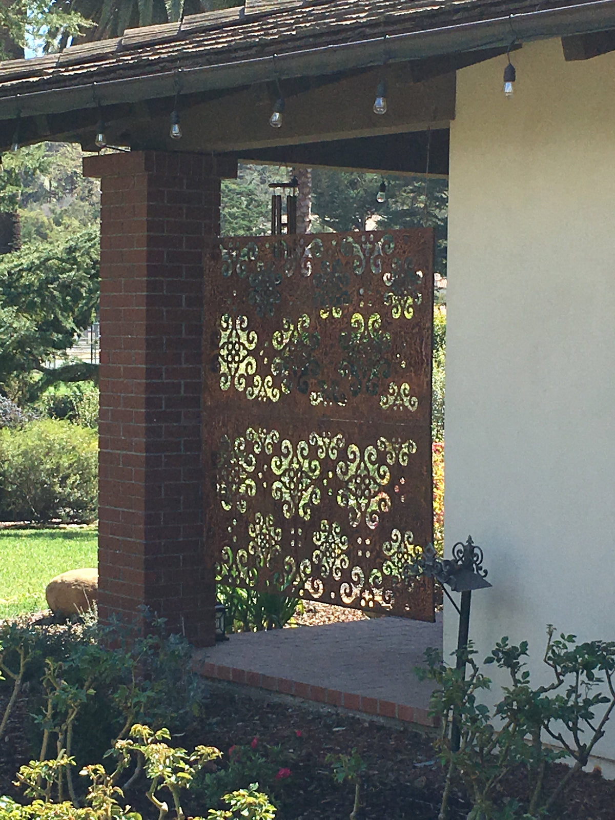 Outdoor privacy panel with ornate scrollwork between brick porch pillars on Tampa Home & Garden Store