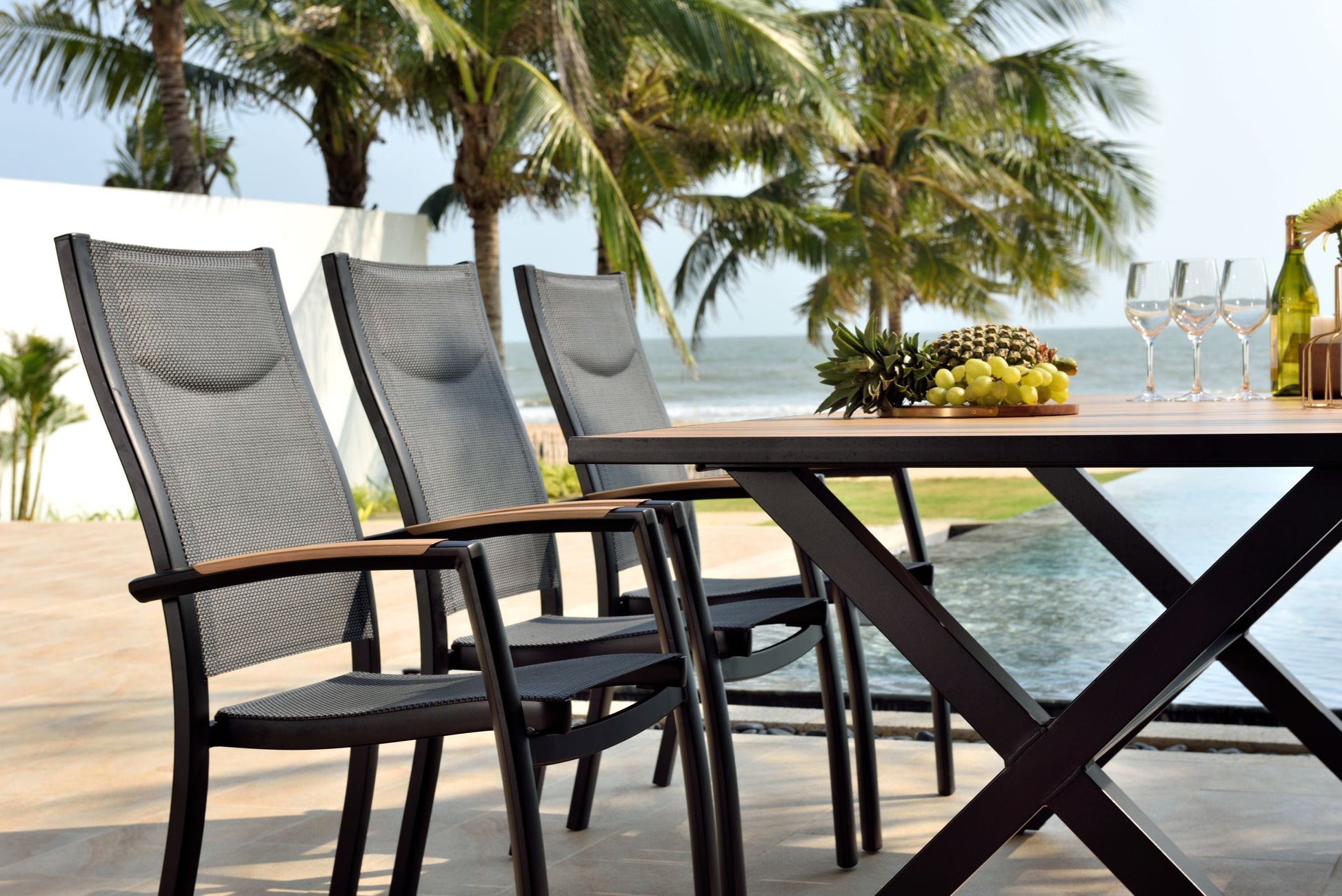 Panama Dark Rectangular Table with black metal frame and mesh seats poolside with fruit and wine on Tampa Home & Garden Store