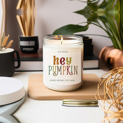 Baked Pumpkin Candle Gia Roma; white soy wax jar with colorful hey PUMPKIN label, lit on a board on Tampa Home & Garden Store