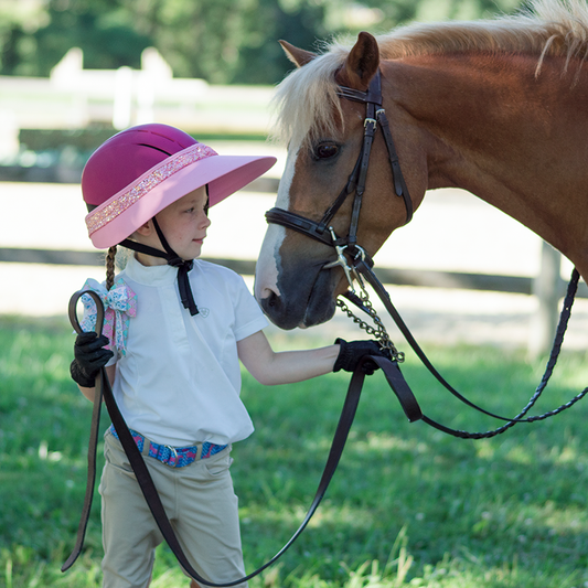 EquiVisor Glitz sun visor in pink with glitter band worn by child beside a horse on Tampa Home & Garden Store