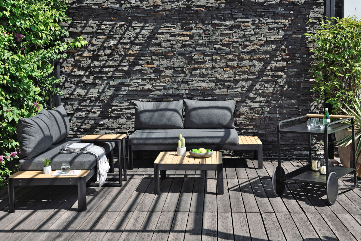 Portals Dark 2-Seat Sofa with dark grey cushions and coffee and two side tables on a wooden deck on Tampa Home & Garden Store