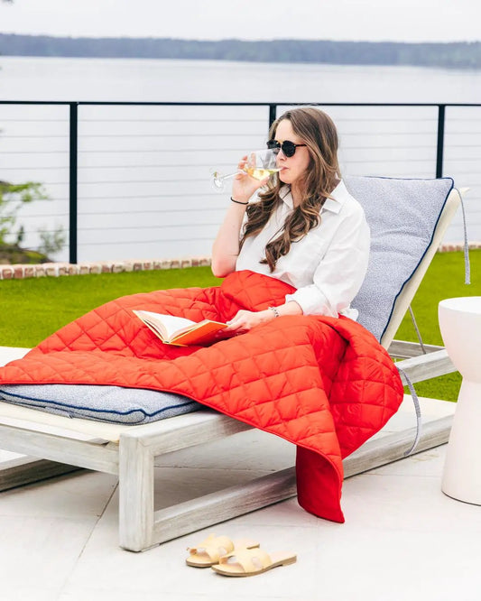 Waterproof Puffer Blanket With Pockets in red on an outdoor lounge chair on Tampa Home & Garden Store