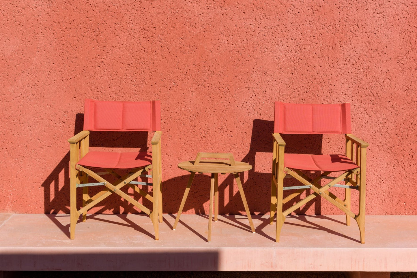 Two red Zircon Teak Director Chairs with a round teak side table on Tampa Home & Garden Store