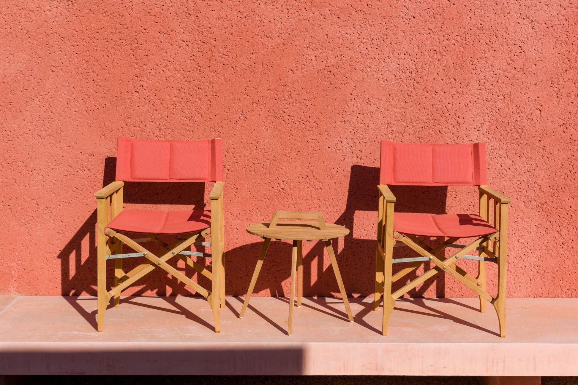 Two red Zircon Teak Director Chairs with a round teak side table on Tampa Home & Garden Store