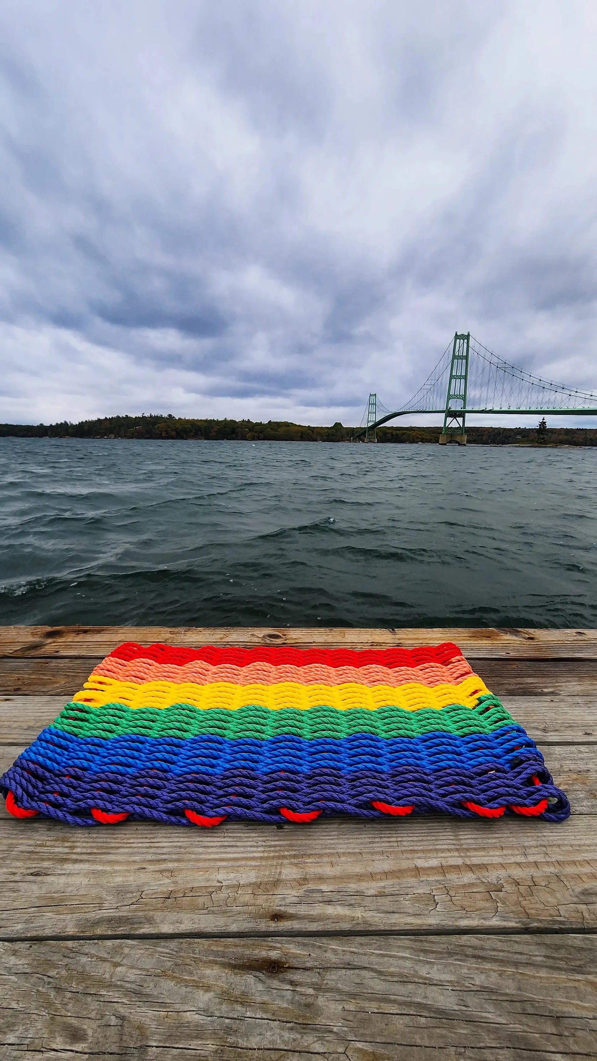 Rainbow Lobster Rope Welcome Mat by Little Salty Rope; rainbow striped rope doormat on a wooden dock on Tampa Home & Garden Store
