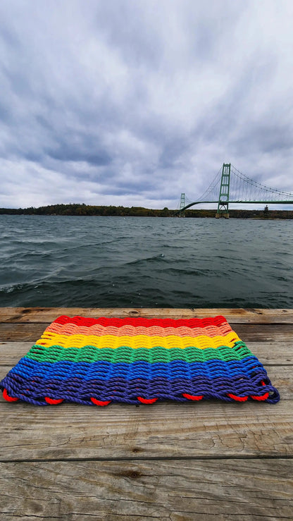 Rainbow Lobster Rope Welcome Mat by Little Salty Rope; rainbow striped rope doormat on a wooden dock on Tampa Home & Garden Store