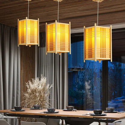 Three solid wooden pendant lights in warm amber glow, Japanese-style over a dining table on Tampa Home & Garden Store