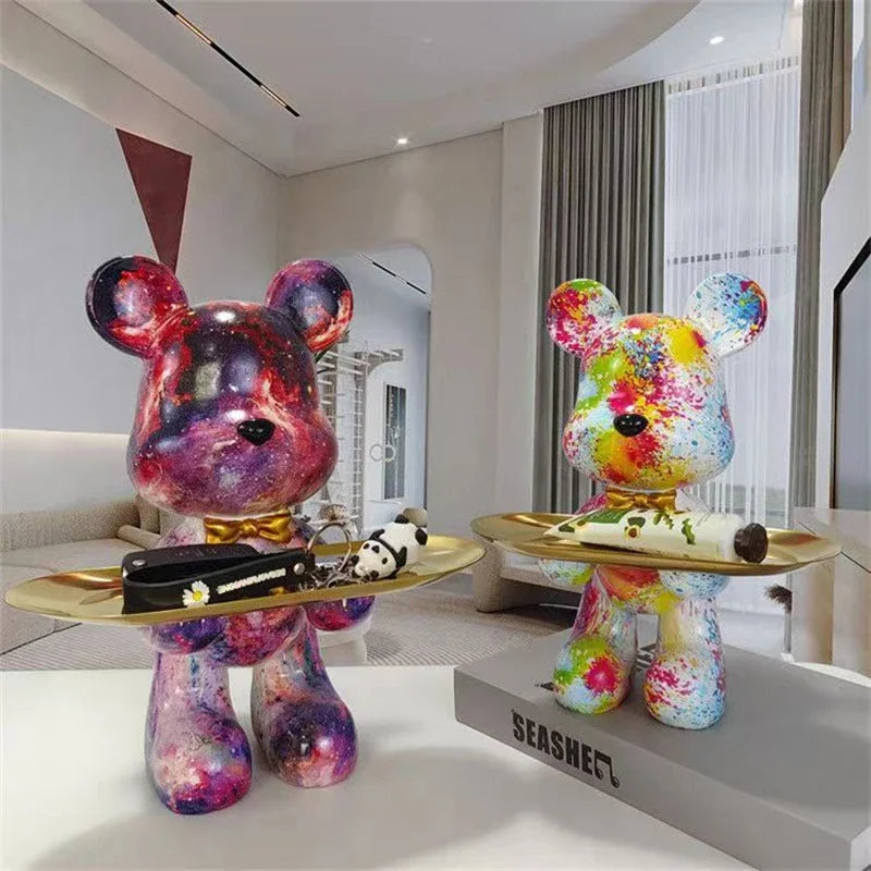 Graffiti bear figurines, two colorful with paint splatters, each holding a gold oval tray on Tampa Home & Garden Store