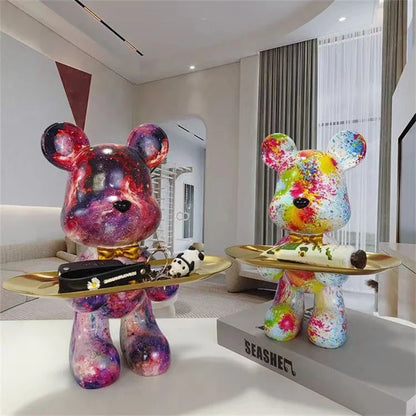 Graffiti bear figurines, two colorful with paint splatters, each holding a gold oval tray on Tampa Home & Garden Store