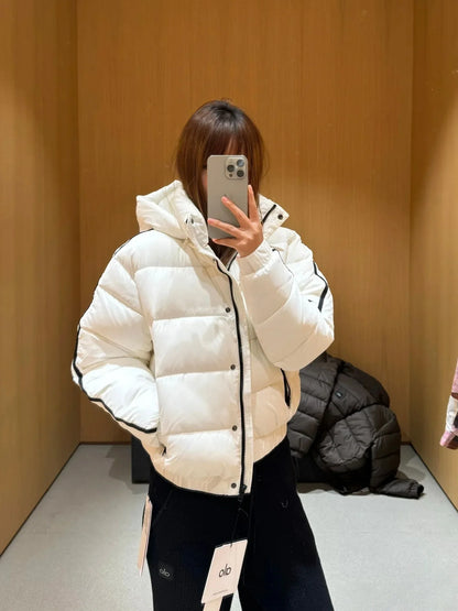 White hooded puffer jacket worn by woman in a fitting room; gray coat on chair in background on Tampa Home & Garden Store
