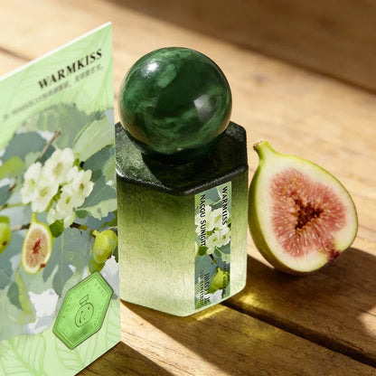 Silcy Skin rose perfume bottle with gradient glass and emerald cap beside Warmkiss box and fig on Tampa Home & Garden Store