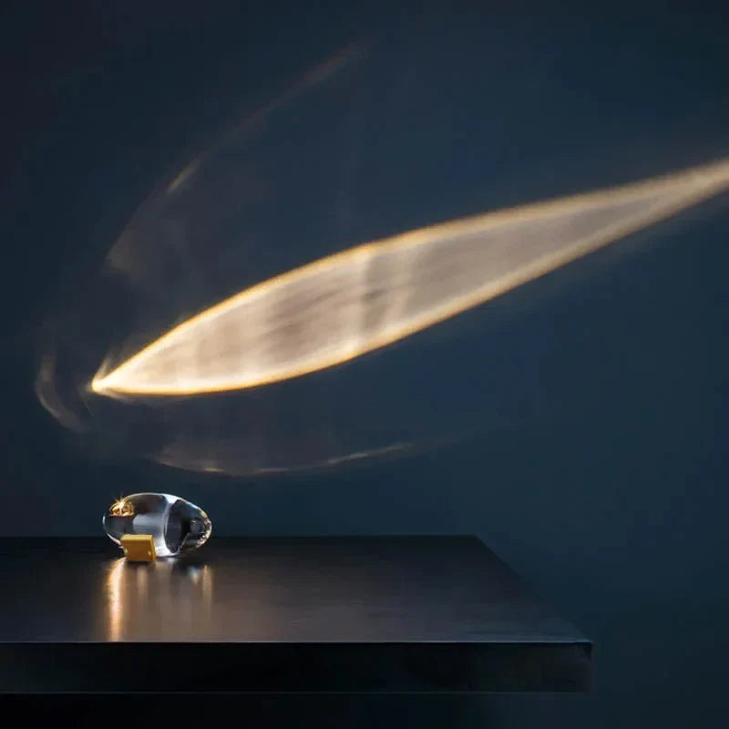Perfecsy Eye Of The Sky LED crystal table lamp with gold base on dark table projecting warm wall glow on Tampa Home & Garden Store