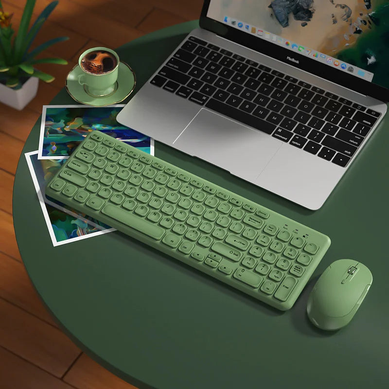 Green wireless keyboard and mouse set with round keys beside a MacBook on a green table on Tampa Home & Garden Store