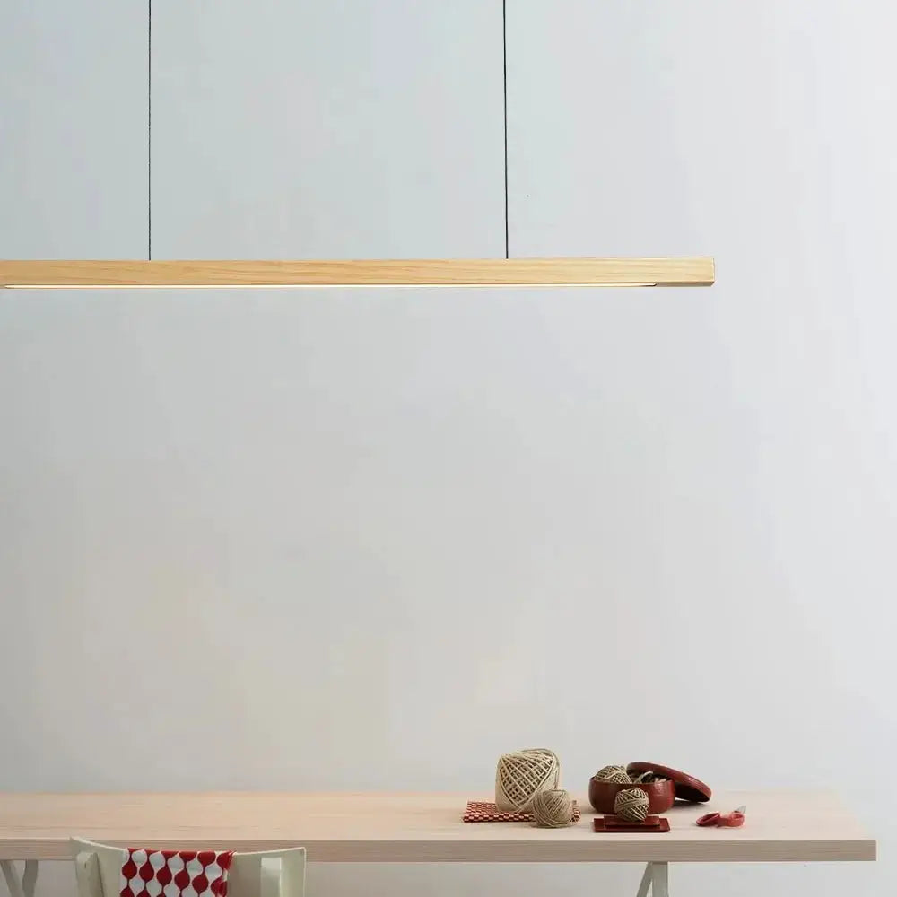 DecorBites linear LED pendant light in natural wood over a light wood dining table in a kitchen on Tampa Home & Garden Store