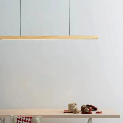 DecorBites linear LED pendant light in natural wood over a light wood dining table in a kitchen on Tampa Home & Garden Store